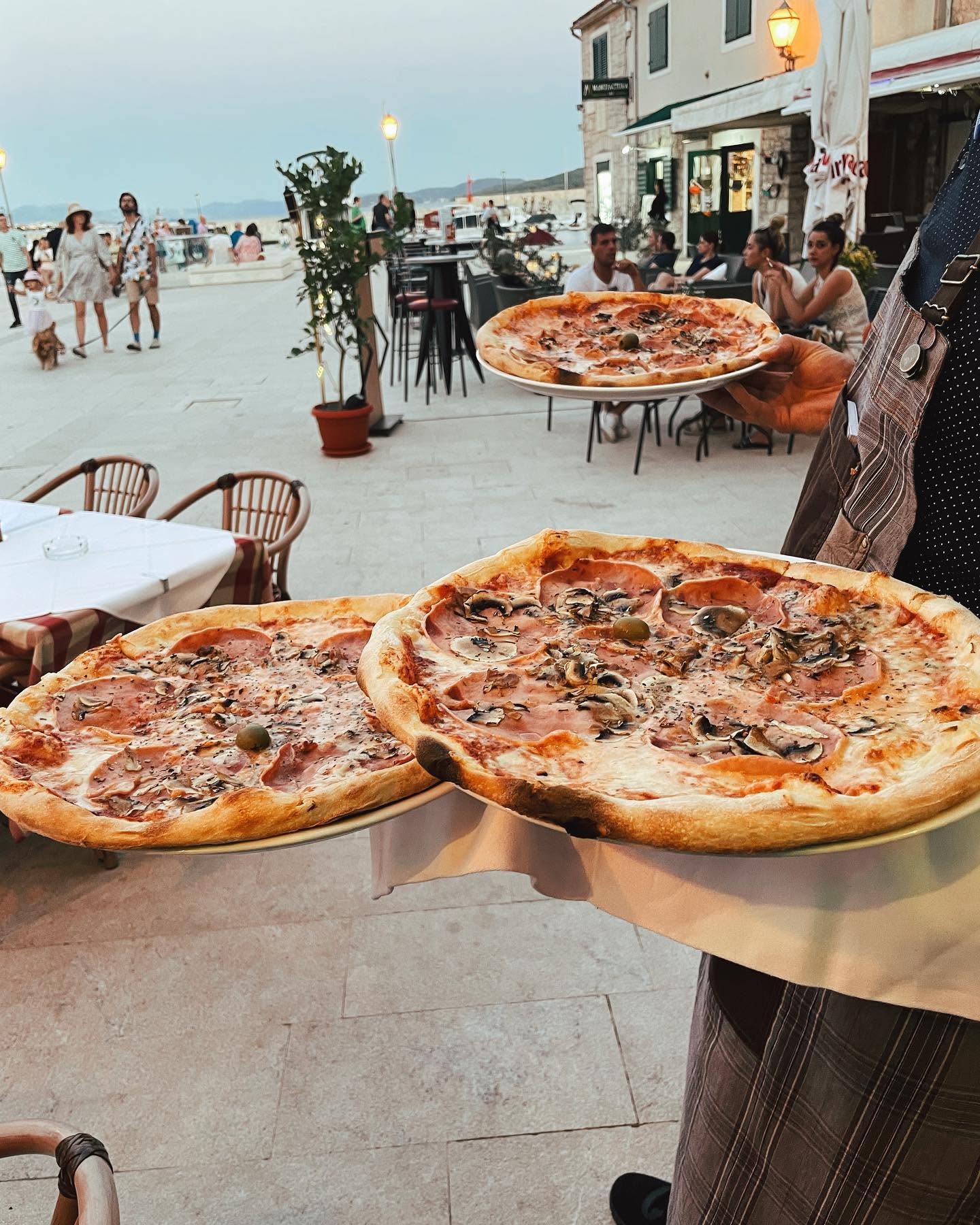Posluživanje triju pizza na terasi HARRY’S u Vodicama